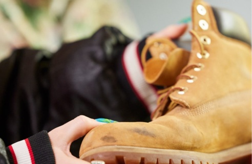 Une personne tenant une botte en cuir usée.