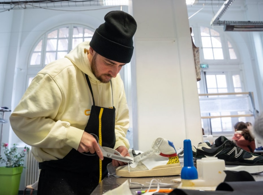 homme répare une chaussure dans un atelier