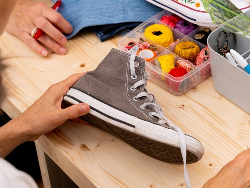 femme fait de la couture sur une chaussure en tissu