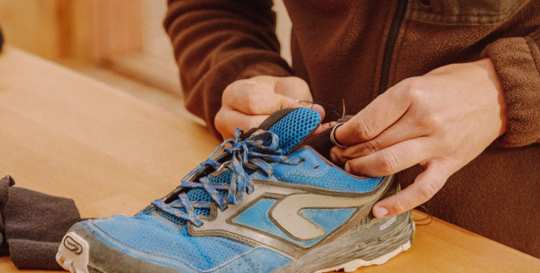 homme répare une paire de chaussure bleu