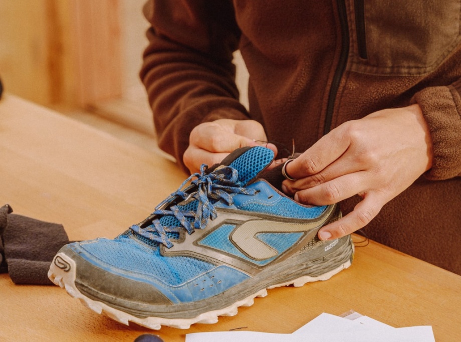 homme répare une paire de chaussure bleu