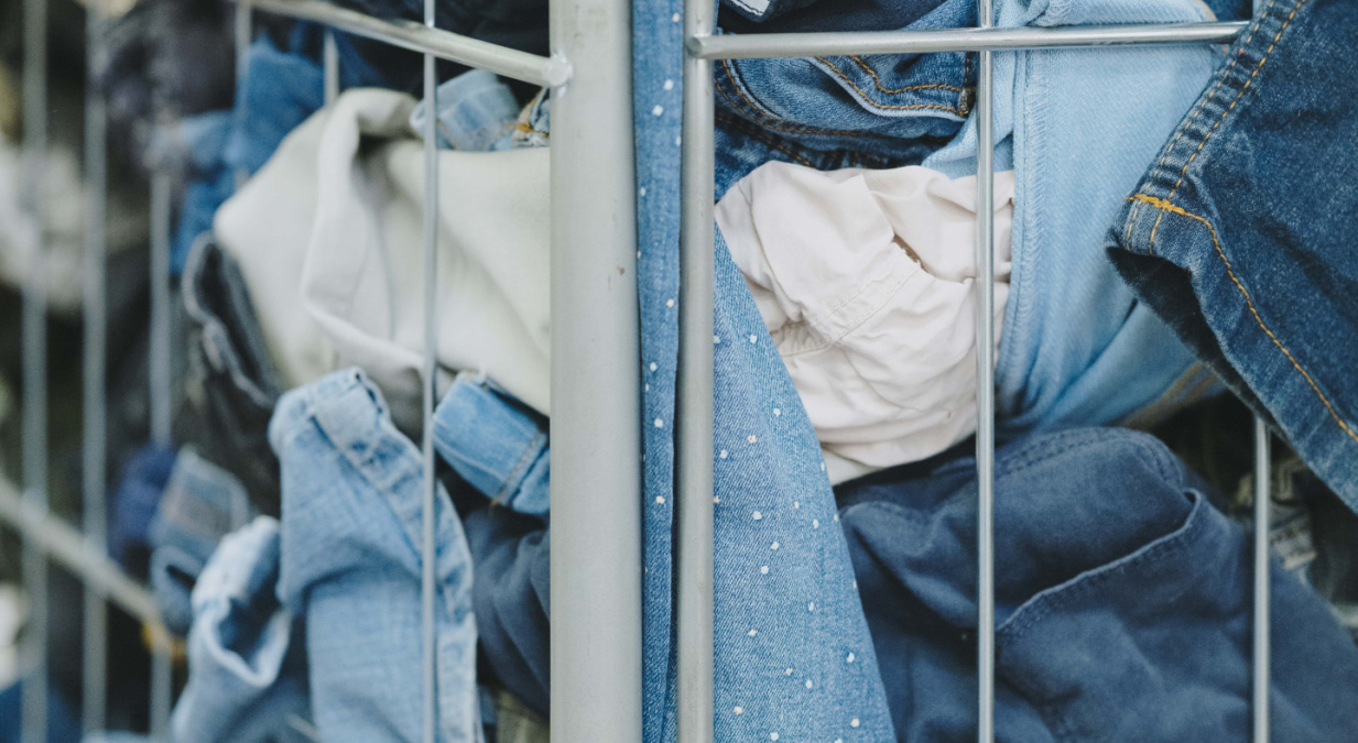 Un chariot rempli de textiles en denim, bien compressés derrière une grille métallique.