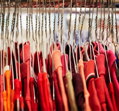 Portant de vêtements : rangée de cintres en métal tenant des habits rouges et colorés.