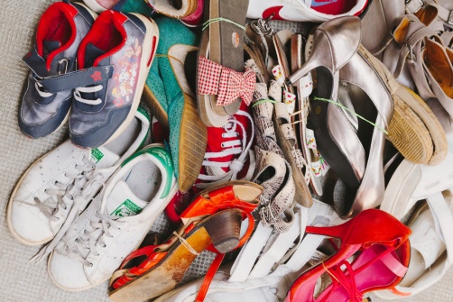 Un tas de chaussures de différents styles, couleurs et tailles, allant des baskets aux talons, attachées par paires avec des élastiques.