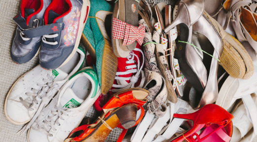 Un tas de chaussures de différents styles, couleurs et tailles, allant des baskets aux talons, attachées par paires avec des élastiques.