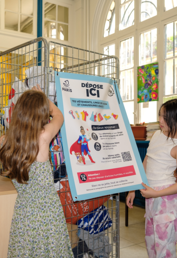 Enfants déposant des sacs de vêtements en point de collecte en école