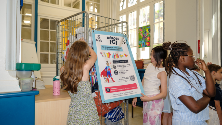 Enfants déposant des sacs de vêtements en point de collecte en école